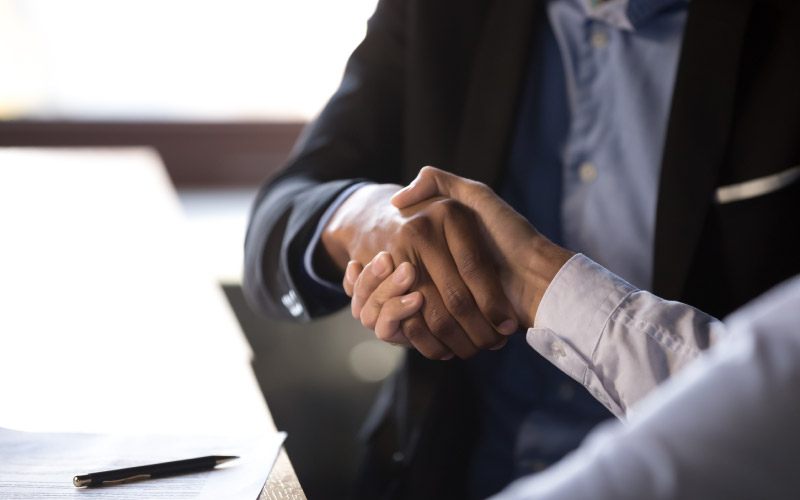 Close-up of African American businessman shaking hands with caucasian client after signing contract