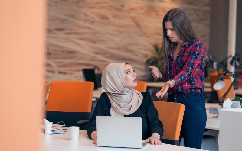 Worried Arabic businesswoman wearing hijab receiving a notification from a colleague in her workplace