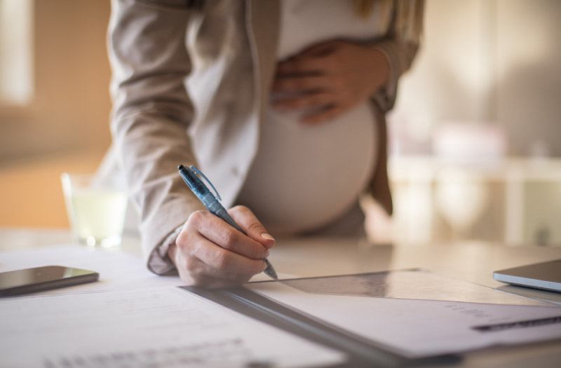 Close-up of pregnant business woman working