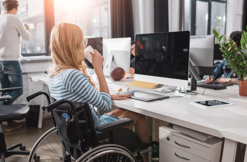 Incapacitated person in wheelchair working at modern office
