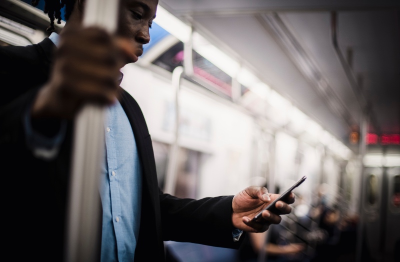 Black man using mobile while commuting by train