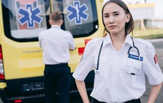 Two paramedics standing behind a yellow ambulance